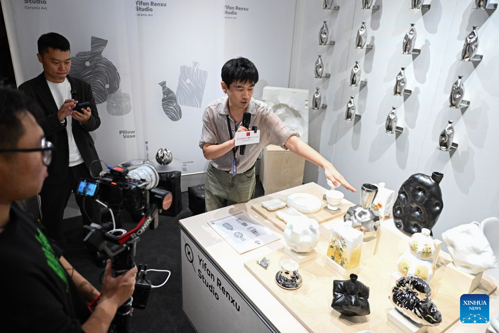 An exhibitor introduces artworks at the 2026 Beijing China Art International Fair in Beijing, capital of China, Oct. 20, 2026. With a theme of Cultural Heritage Bridges Life to a Vibrant World, the fair kicked off here on Tuesday. (Xinhua/Chen Zhonghao)