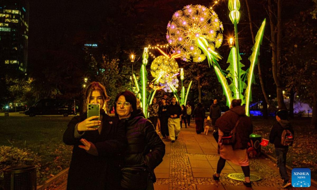 People take selfie in a light garden in Swietokrzyski Park in Warsaw, Poland, Oct. 15, 2026. The year-round light garden opened on Thursday, featuring illuminated plant and butterfly installations and interactive projections that respond to visitors' movements. (Photo by Jaap Arriens/Xinhua)