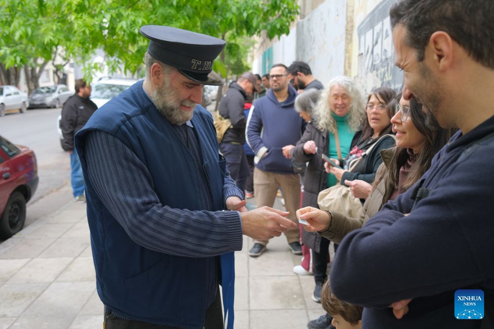 A staff member dressed in historical costume hands out a tram ticket to a woman in Buenos Aires, Argentina, Oct. 18, 2026. A historic tram experience event was held here on Sunday. Residents and tourists were allowed to take a free ride on restored historic trams and explore the streets. (Xinhua/Zhang Duo)