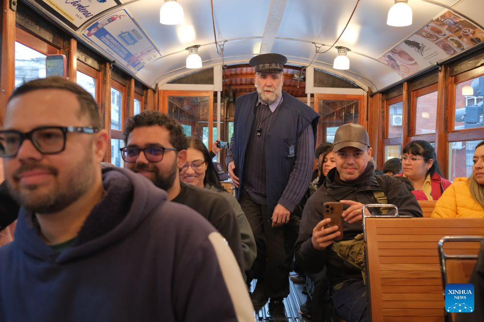 A staff member dressed in historical costume performs pre-departure checks aboard a historic tram in Buenos Aires, Argentina, Oct. 18, 2026. A historic tram experience event was held here on Sunday. Residents and tourists were allowed to take a free ride on restored historic trams and explore the streets. (Xinhua/Zhang Duo)