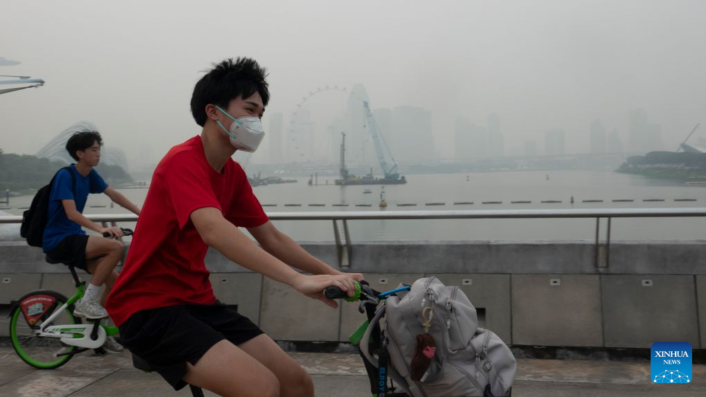 People ride amid the haze at the Marina Bay area in Singapore, Oct. 15, 2026. (Xinhua/Then Chih Wey)