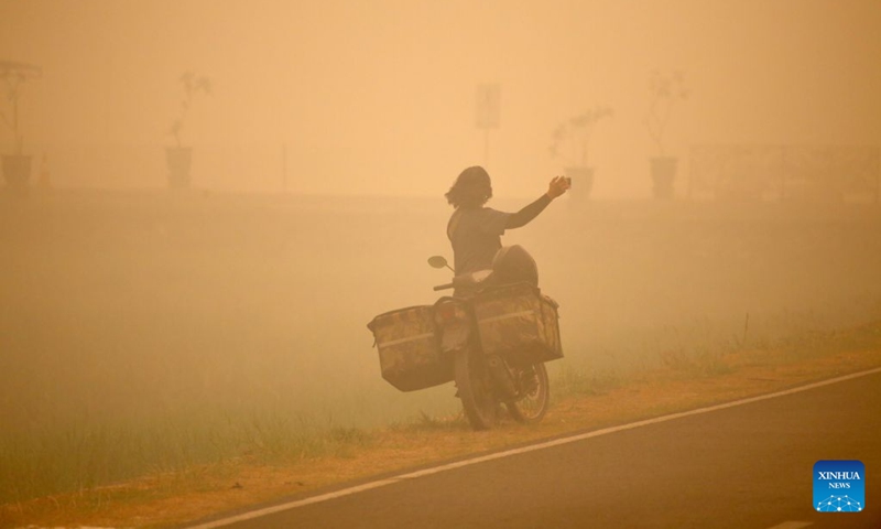 A person takes photos amid thick haze caused by forest and peatland fires in Palangka Raya, Central Kalimantan, Indonesia, Oct. 13, 2026. (Photo: Xinhua)