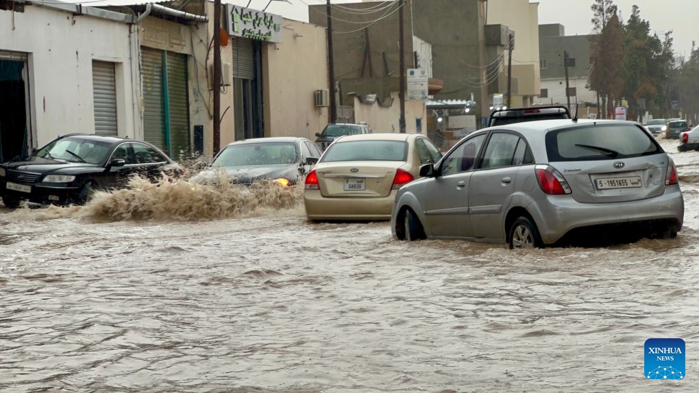 This photo taken with a mobile phone shows vehicles running on a flooded road after heavy rains in Tripoli, Libya, Oct. 13, 2026. (Photo: Xinhua)