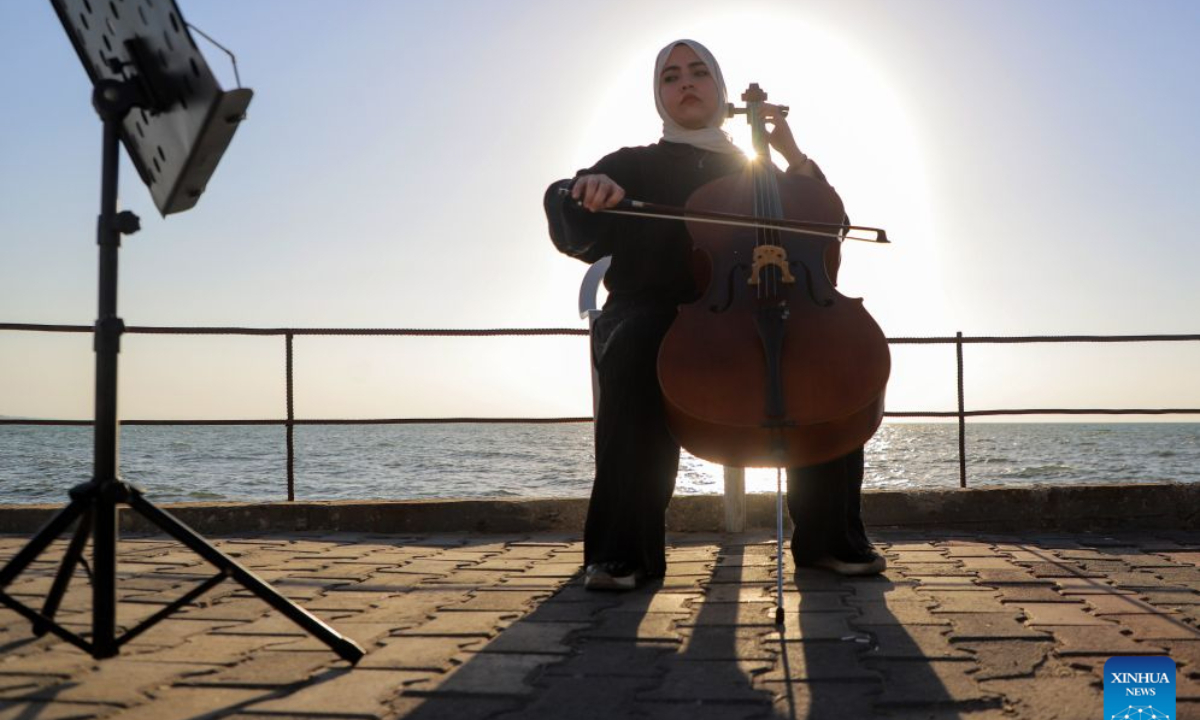 Palestinian artist Haifa Bassam Abu Shamla plays the cello at a cafe near the seaside in Gaza City, on Oct. 4, 2026. (Photo by Rizek Abdeljawad/Xinhua)