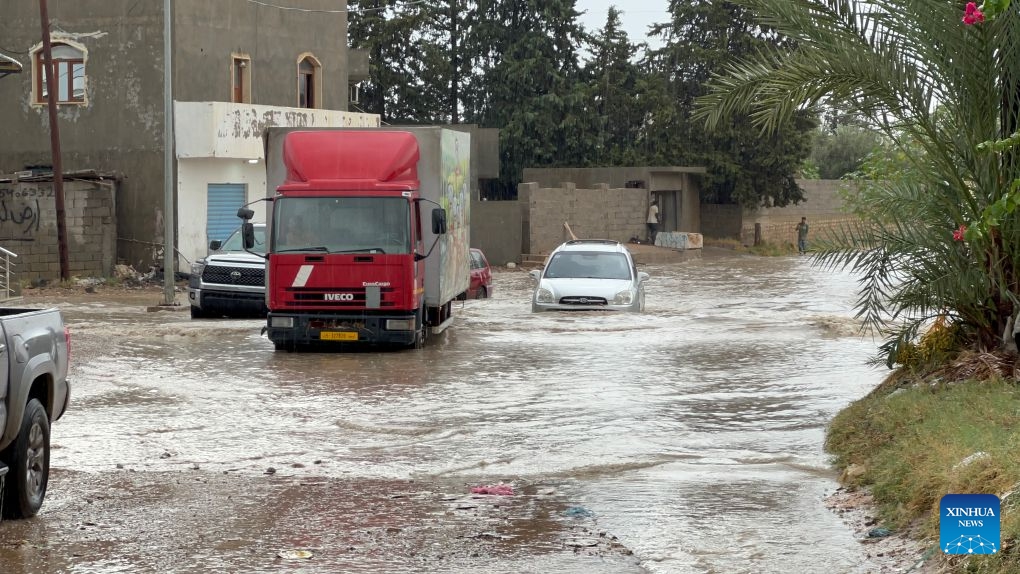 This photo taken with a mobile phone shows vehicles running on a flooded road after heavy rains in Tripoli, Libya, Oct. 13, 2026. (Photo: Xinhua)