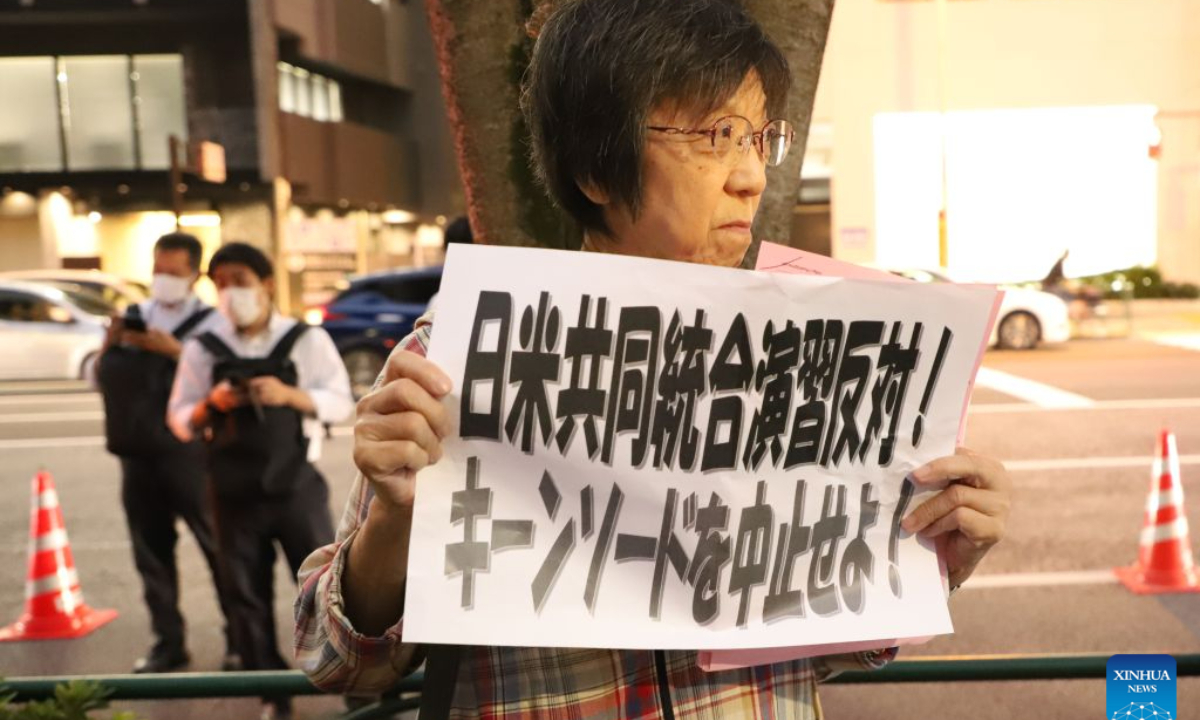A protestor holding a sign attends a protest rally in Tokyo, Japan, Oct. 20, 2026. Japanese citizens staged a protest rally in front of the Ministry of Defense in Tokyo on Tuesday evening, opposing the large-scale Japan-U.S. joint military exercises and the military buildup. (Xinhua/Li Ziyue)