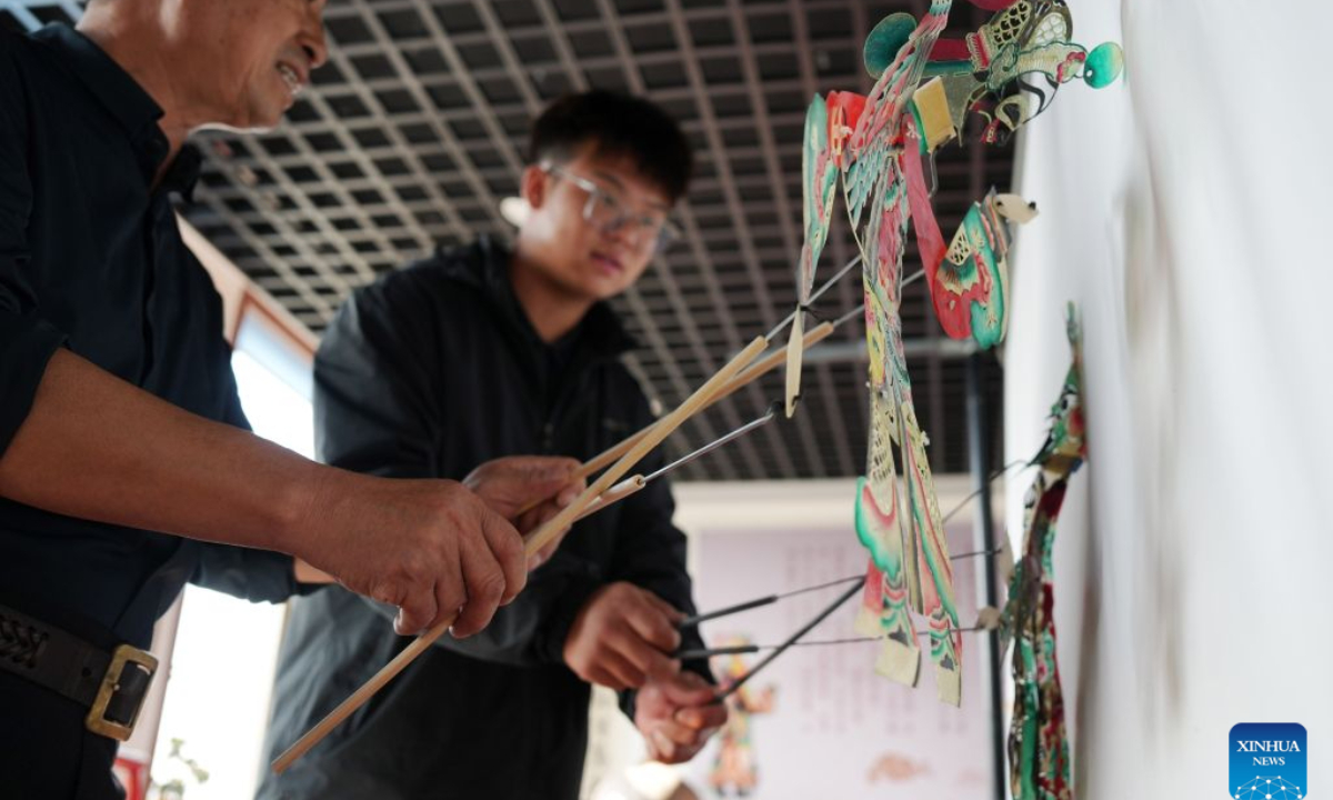 Xu Zilin (L) instructs one of his apprentices on shadow puppetry maneuver in Lingyuan City, northeast China's Liaoning Province, Oct. 10, 2026.(Xinhua/Li Gang)