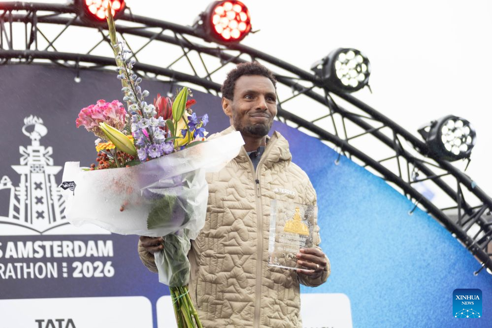 Lemi Berhanu of Ethiopia displays his trophy on the awarding podium after winning the men's race of the Amsterdam Marathon in Amsterdam, the Netherlands, Oct. 18, 2026. (Photo by Sylvia Lederer/Xinhua)