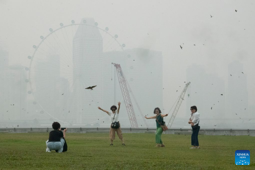 People pose for photos amid the haze at the Marina Bay area in Singapore, Oct. 15, 2026. (Xinhua/Then Chih Wey)