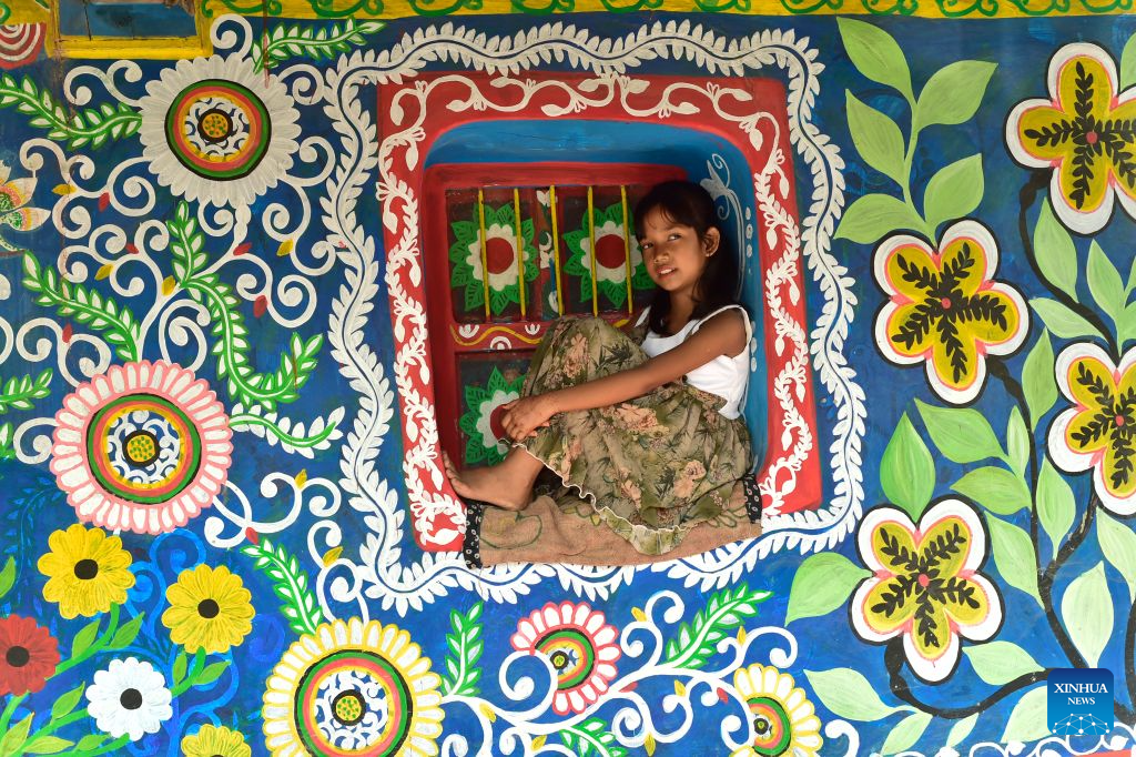 A child is seen at a house decorated with Alpona in a village in Chapainawabganj District, Bangladesh, Oct. 18, 2026. Alpona is a traditional form of folk art practiced in South Asia and is mainly created by women in the local community. (Photo by Habibur Rahman/Xinhua)