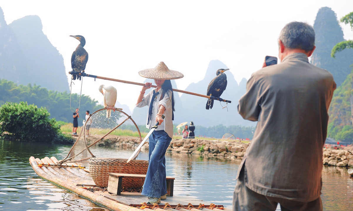 A tourist poses for a photo on a bamboo raft along the Li River in Guilin, South China's Guangxi Zhuang Autonomous Region on October 15, 2026. The World Canals Conference runs from October 12 to October 15 in Guilin and the Li River is on one of its three field visit routes. Photo: Cui Meng/Global Times