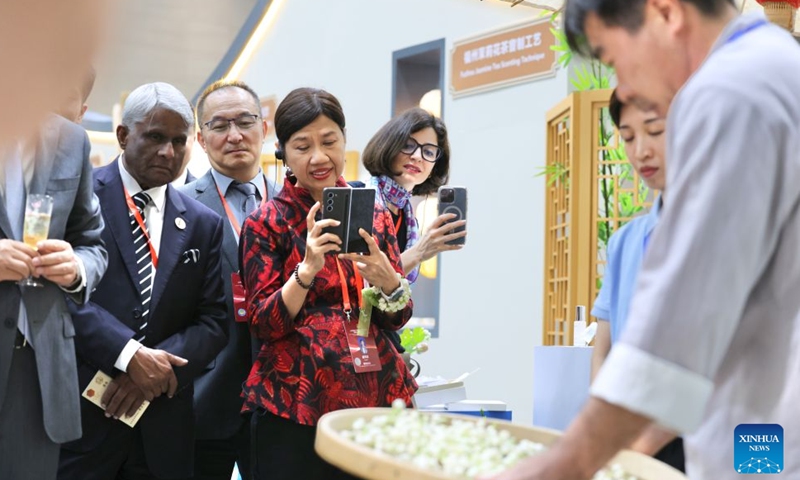 Participants of the 21st Century Maritime Silk Road Local Government Cooperation and International Friendship Cities Dialogue watch the making process of jasmine tea at a Fujian intangible cultural heritage exhibition in Fuzhou, southeast China's Fujian Province, Oct. 17, 2026. (Xinhua/Jiang Kehong)