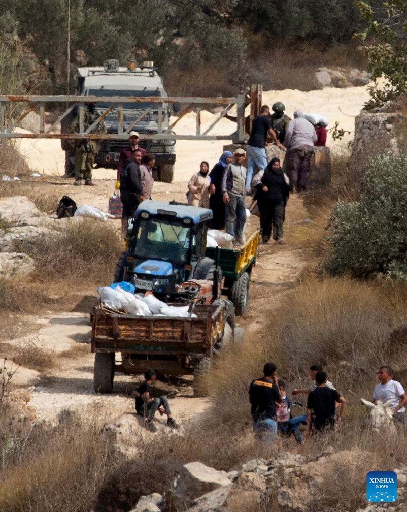 Palestinian farmers are seen at an Israeli military checkpoint after the forces prevented them from harvesting olives at their lands, in the village of Salem, east of Nablus, in the West Bank, on Oct. 17, 2026. (Photo by Nidal Eshtayeh/Xinhua)