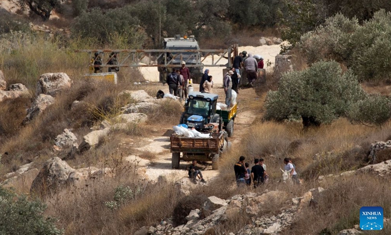 Palestinian farmers are seen at an Israeli military checkpoint after the forces prevented them from harvesting olives at their lands, in the village of Salem, east of Nablus, in the West Bank, on Oct. 17, 2026. (Photo by Nidal Eshtayeh/Xinhua)
