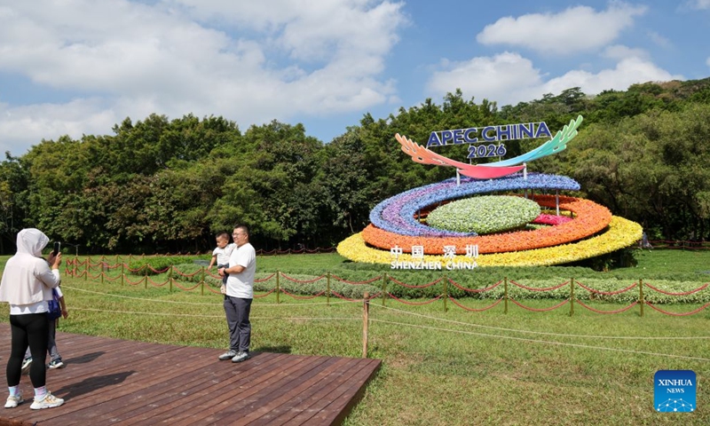 People pose for photos with a flower decoration themed on the 2026 APEC China Year, in Shenzhen, south China's Guangdong Province, Oct. 17, 2026. The APEC Economic Leaders' Meeting will be held in Shenzhen next month. (Xinhua/Liang Xu)