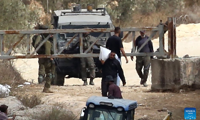 Palestinian farmers are seen at an Israeli military checkpoint after the forces prevented them from harvesting olives at their lands, in the village of Salem, east of Nablus, in the West Bank, on Oct. 17, 2026. (Photo by Nidal Eshtayeh/Xinhua)