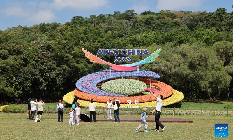 People pose for photos with a flower decoration themed on the 2026 APEC China Year, in Shenzhen, south China's Guangdong Province, Oct. 17, 2026. The APEC Economic Leaders' Meeting will be held in Shenzhen next month. (Xinhua/Liang Xu)