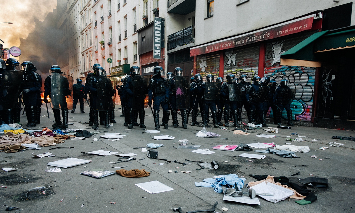 Riot police stand amid debris and smoke on a street in Paris, France, on October 18, 2026, following large-scale demonstrations the previous day. Photo: VCG