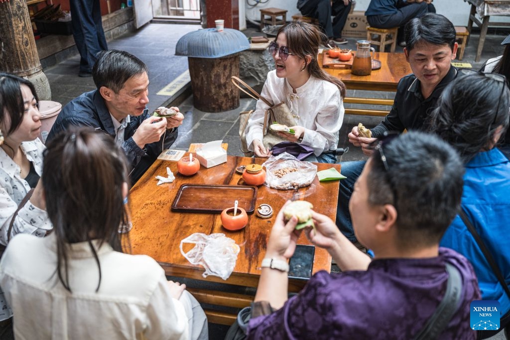 Tourists enjoy local snacks in Simola Wa Village in Qingshui Town of Tengchong City, southwest China's Yunnan Province, Oct. 19, 2026. The Simola Wa Village has a history of over 500 years and is home to people of multiple ethnic groups including the Wa, Han, Bai and Dai. Simola means a place of happiness in the Wa language. In recent years, the village has relied on its ethnic cultural resources to create a distinctive cultural tourism industry, attracting a continuous stream of tourists. (Photo: Xinhua)