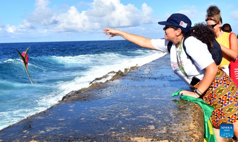A woman throws flowers into the sea during a ceremony commemorating Camilo Cienfuegos in Havana, capital of Cuba, on Oct. 28, 2026. Cuba marked the 67th anniversary of the death of Camilo Cienfuegos. Cienfuegos, along with Fidel Castro and Che Guevara, are the three chief commanders of the Cuban revolution. He died in a flight accident at the age of 27. (Photo: Xinhua)