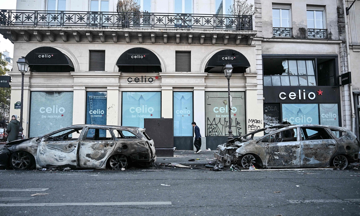 A pedestrian walks past two burnt vehicles parked on a street in Paris, France on October 18, 2026,a day after nationwide protests against the high cost of living. Photo: VCG 