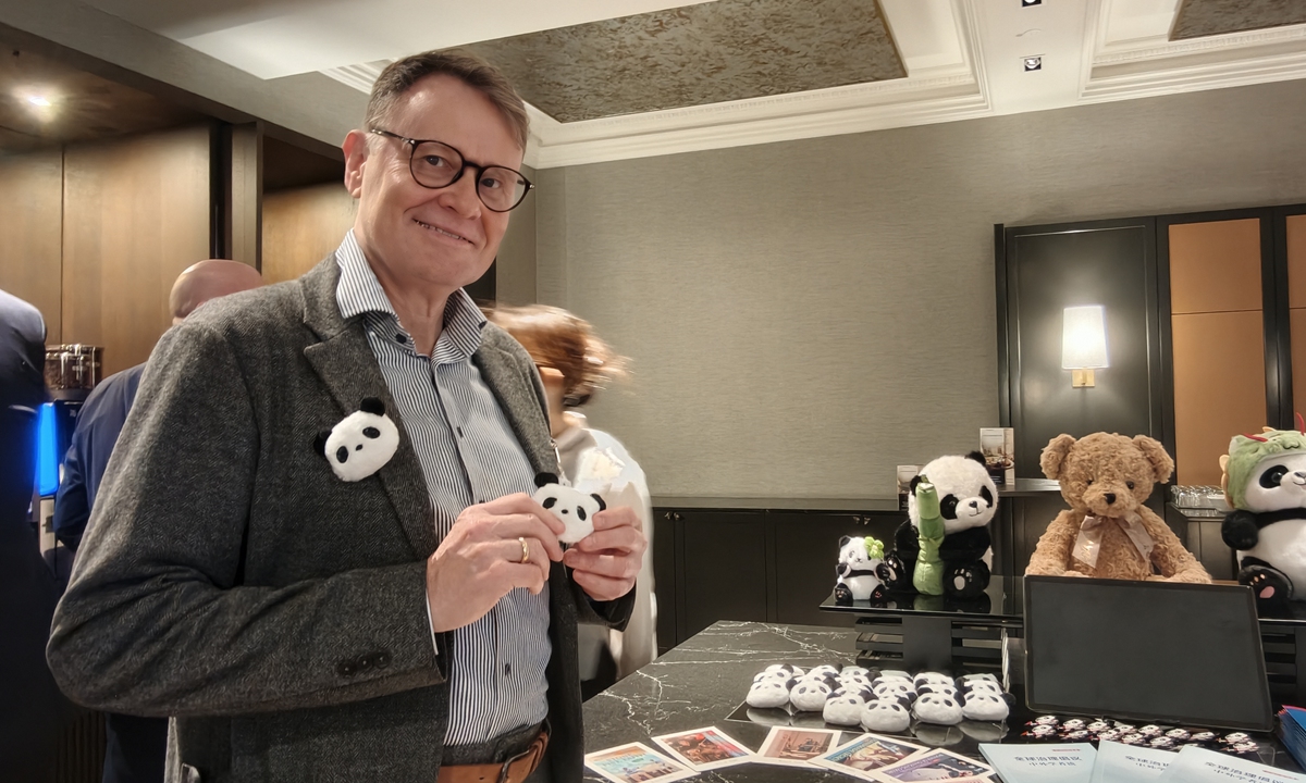 J?rg Lau, international correspondent for German media Die Zeit, visits the photo exhibition and tries the panda brooch. Photo: Hu Yuwei/GT