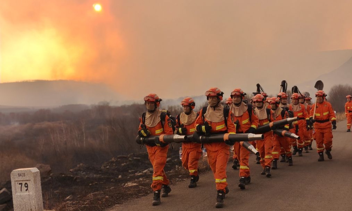 Firefighters patrol with fire extinguishing equipment at the border area in north China's Inner Mongolia Autonomous Region. More than 2,000 personnel were deployed in north China's Inner Mongolia Autonomous Region to contain a grassland fire spreading from Mongolia, local authorities said on October 11. Photo: Xinhua