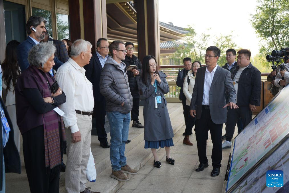 Participants of the 2026 Global Governance Forum (Xiong'an) listen to the introduction of the construction of Xiong'an New area while visiting the start-up zone of Xiong'an in north China's Hebei Province, Oct. 23, 2026. The 2026 Global Governance Forum (Xiong'an) kicked off here on Friday and will last till Sunday. Participants from various countries and regions visited a smart-city science and innovation center and the construction site of the start-up zone of Xiong'an New Area ahead of the forum. (Xinhua/Su Kaiyang)