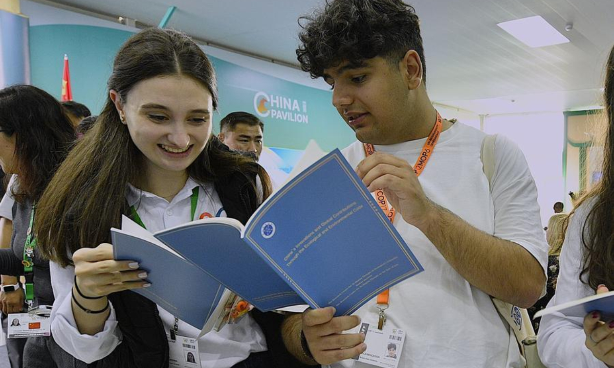 Guests read the English version of the think tank report titled China's Innovations and Global Contributions Through the Ecological and Environmental Code in Yerevan, Armenia, Oct. 21, 2026. (Xinhua/Chen Junfeng)
