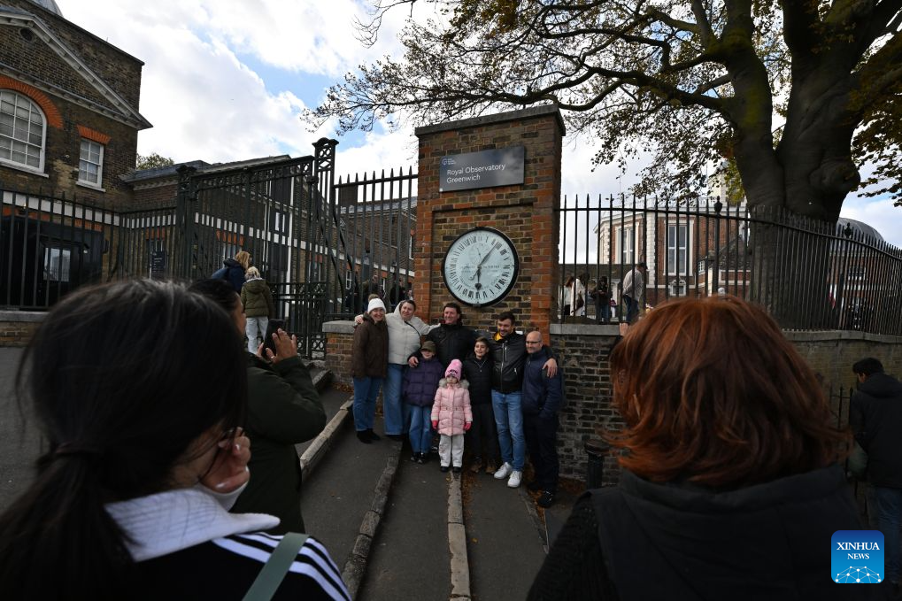 Visitors pose for photos with the Shepherd Gate Clock at the entrance to the Royal Observatory in Greenwich, London, Britain, on Oct. 25, 2026. The clock was the world's first to display Greenwich Mean Time (GMT) directly to the public and features a 24-hour dial. Britain ended British Summer Time (BST) at 2am on Sunday, October 25, 2026, setting clocks back one hour to Greenwich Mean Time (GMT). (Xinhua/Li Mangmang)