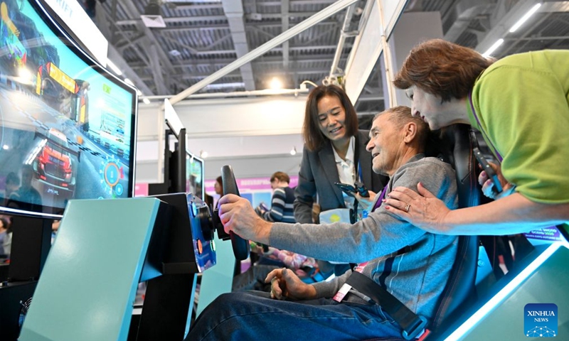 A visitor tries video game devices at the 48th International Exhibition of Amusement Rides and Entertainment Equipment in Moscow, Russia, Oct. 21, 2026. (Photo by Alexander Zemlianichenko Jr/Xinhua)