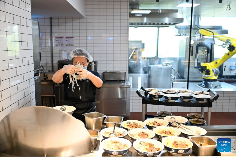 A staff member works at the AI Mirror World Restaurant in Nanjing, east China's Jiangsu Province, Oct. 26, 2026. With a human-machine collaborative operation model, the restaurant makes some of its meals and drinks through standardized production powered by AI kitchen equipped with smart noodle and beverage making machines. (Xinhua/Ji Chunpeng)