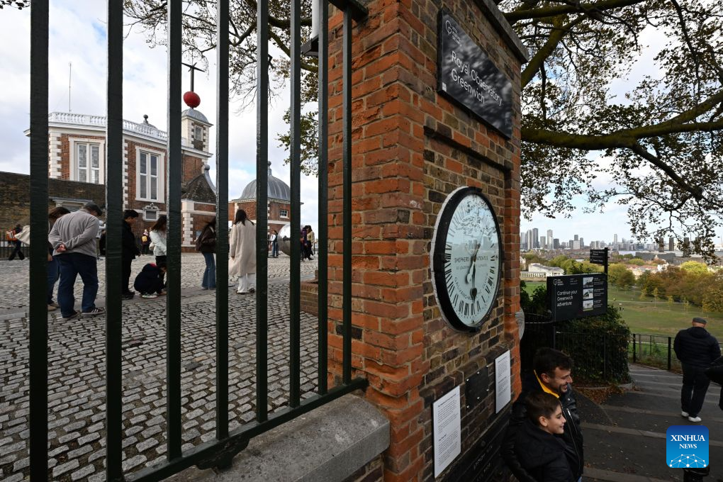 Visitors pose for photos with the Shepherd Gate Clock at the entrance to the Royal Observatory in Greenwich, London, Britain, on Oct. 25, 2026. The clock was the world's first to display Greenwich Mean Time (GMT) directly to the public and features a 24-hour dial. Britain ended British Summer Time (BST) at 2am on Sunday, October 25, 2026, setting clocks back one hour to Greenwich Mean Time (GMT). (Xinhua/Li Mangmang)
