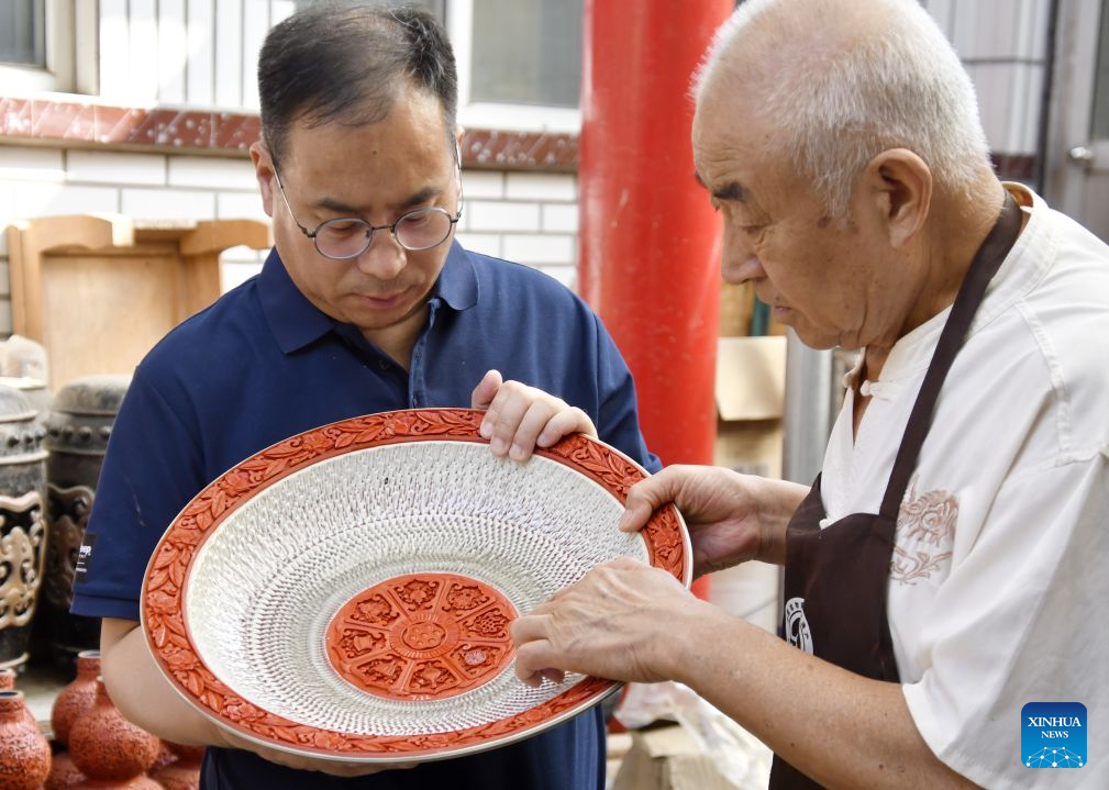 Zhu Jiang (L) checks a piece of work of the carved lacquer craft on porcelain body with his father, who is also a master of the carved lacquer art, in Beijing, capital of China, Oct. 26, 2026.

Born in 1976, Zhu Jiang, a master of arts and crafts of Beijing, is an inheritor of the carved lacquer art.

The carved lacquer craft on porcelain body is a unique art form that combines two traditional Chinese crafts, porcelain and carved lacquerware making, into a single piece.

Through years of studying and practicing, Zhu has overcome a series of difficulties to achieve a better presentation of this craft. (Xinhua/Li Xin)