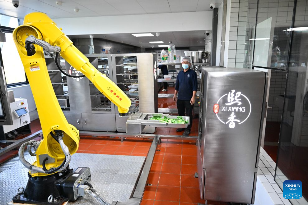 A robotic arm transports ingredients in the kitchen of the AI Mirror World Restaurant in Nanjing, east China's Jiangsu Province, Oct. 26, 2026. With a human-machine collaborative operation model, the restaurant makes some of its meals and drinks through standardized production powered by AI kitchen equipped with smart noodle and beverage making machines. (Xinhua/Ji Chunpeng)