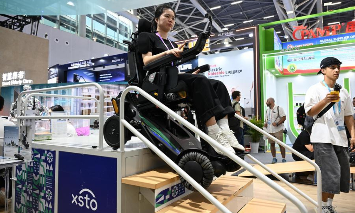 A staff member controls a smart wheelchair to go down the stairs during the Canton Fair in Guangzhou, south China's Guangdong Province, Oct. 15, 2026. (Xinhua/Deng Hua)