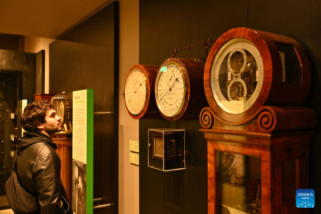 A visitor looks at exhibits themed on Greenwich Mean Time at the Royal Observatory in Greenwich, London, Britain, on Oct. 25, 2026. The Royal Observatory in Greenwich was founded in 1675 to improve navigation at sea through astronomical observations and help ships determine their longitude. As the home of Greenwich Mean Time, it holds an important place in the history of astronomy, precision timekeeping and navigation. In 1884, the meridian passing through the observatory was adopted as the international Prime Meridian, establishing a common reference for measuring longitude worldwide. This historic line is still marked at the observatory today. (Xinhua/Li Mangmang)