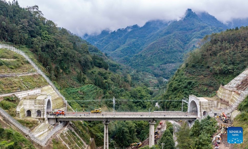An aerial drone photo taken on Oct. 24, 2026 shows the construction site at the Junlian tunnel of the Chongqing-Kunming high-speed railway on the border of southwest China's Yunnan Province and southwest China's Sichuan Province. The last pair of 500-meter-long steel rails was steadily placed on the track on Saturday, marking the official completion of track laying for the Chongqing-Kunming high-speed railway. (Xinhua/Hu Chao)