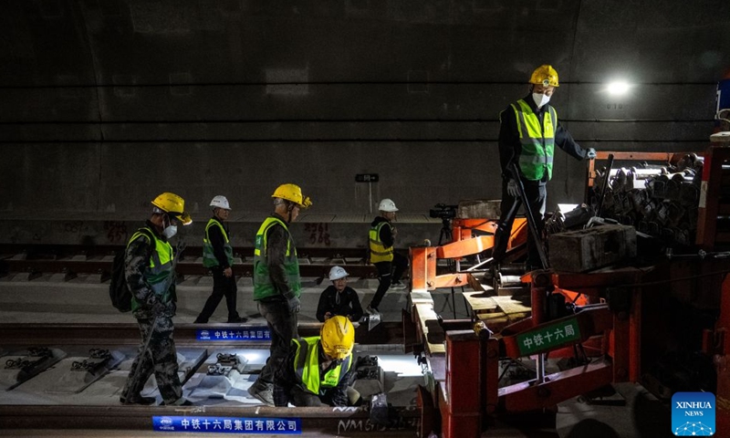 Workers lay tracks at the Junlian tunnel of the Chongqing-Kunming high-speed railway on the border of southwest China's Yunnan Province and southwest China's Sichuan Province, Oct. 24, 2026. The last pair of 500-meter-long steel rails was steadily placed on the track on Saturday, marking the official completion of track laying for the Chongqing-Kunming high-speed railway. (Xinhua/Hu Chao)