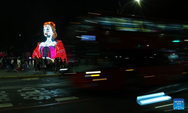 A bus passes by a Catrina-shaped light art installation along Paseo de la Reforma in Mexico City, capital of Mexico, Oct. 23, 2026. As the Day of the Dead approaches, giant light sculptures along Paseo de la Reforma in Mexico City, capital of Mexico, are illuminated. (Photo by Francisco Canedo/Xinhua)
