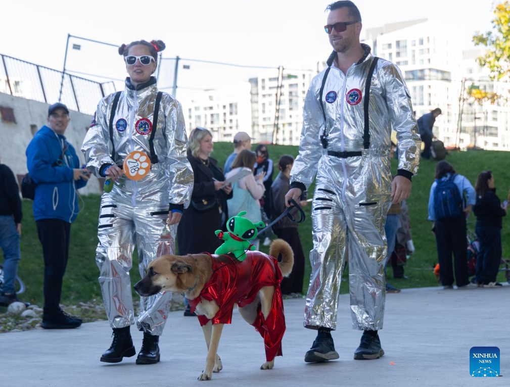 A dog and its owners take part in Howl'oween at the Bentway, a dog-and-owner costume contest, in Toronto, Canada, on Oct. 24, 2026. The annual event was held here on Saturday, bringing Halloween fun for dogs and their owners. (Photo by Zou Zheng/Xinhua)