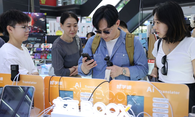 This photo taken on June 24, 2026 shows tourists from South Korea experiencing AI translator at Huaqiangbei of Shenzhen, south China's Guangdong Province. (Xinhua/Liang Xu)
